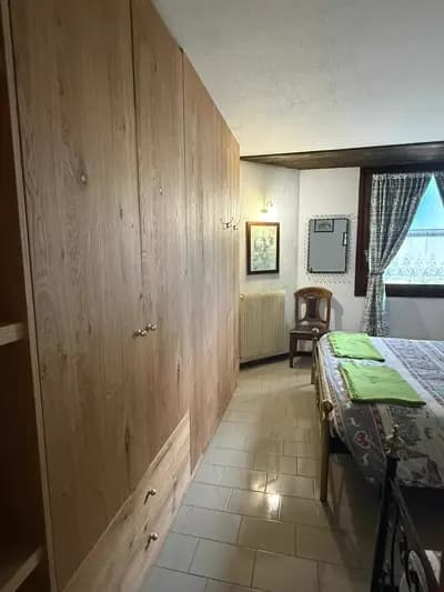 Camera da letto con grande finestra, letto matrimoniale con struttura in metallo dorato e vetrata decorativa sovrastante