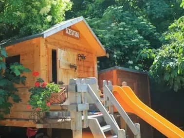 Una casetta di legno per bambini, con scivolo, nel giardino del Residence