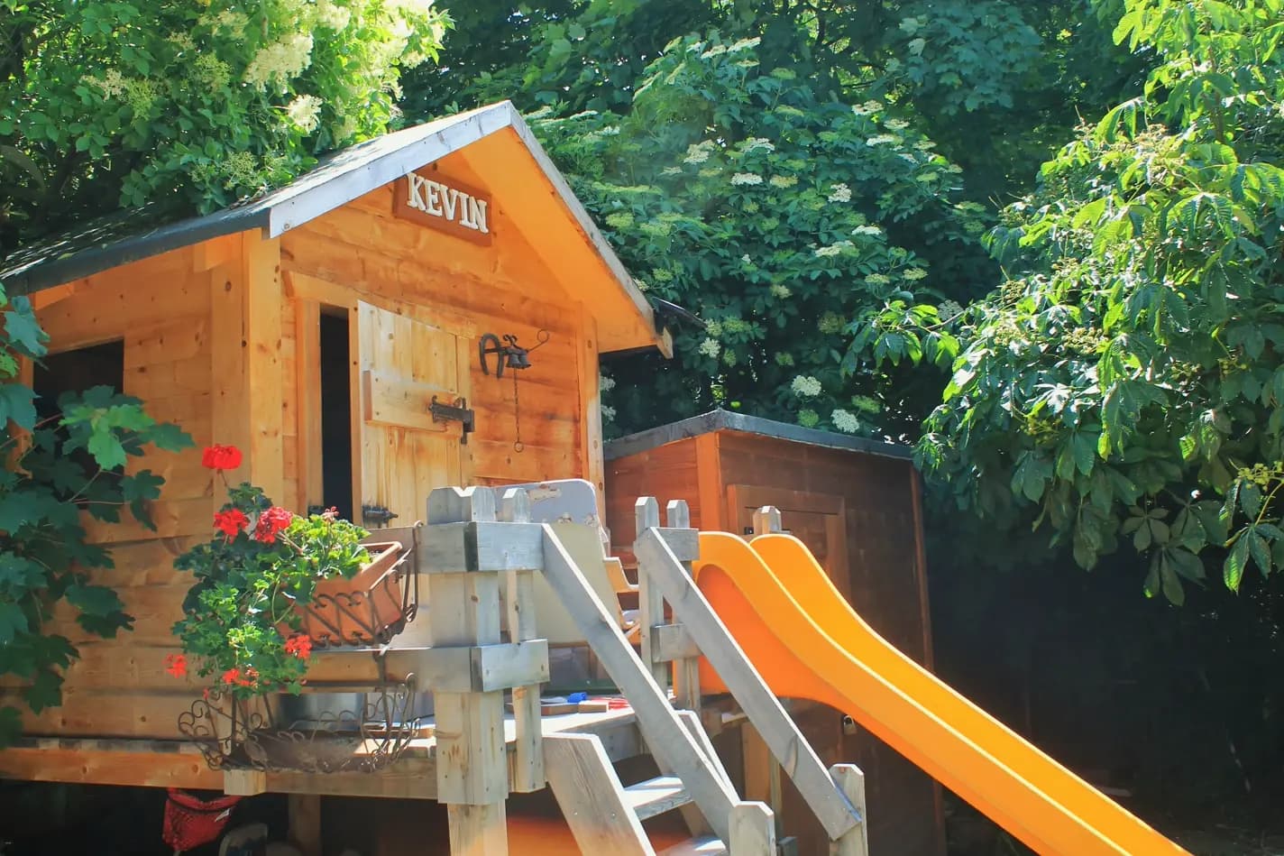 Una casetta di legno per bambini, con scivolo, nel giardino del Residence